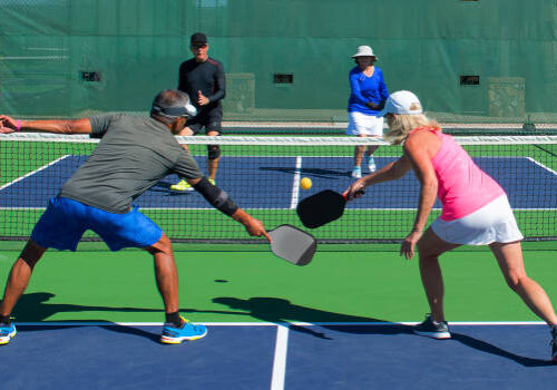 colorful action image of two couples playing pickleball in a mixed doubles match